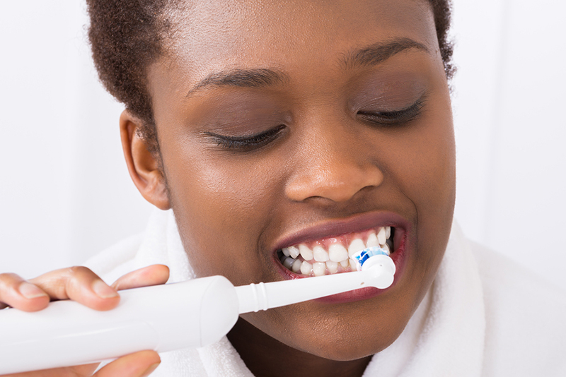 Close-up Of A Young African Woman Brushing Teeth With Electric Brush