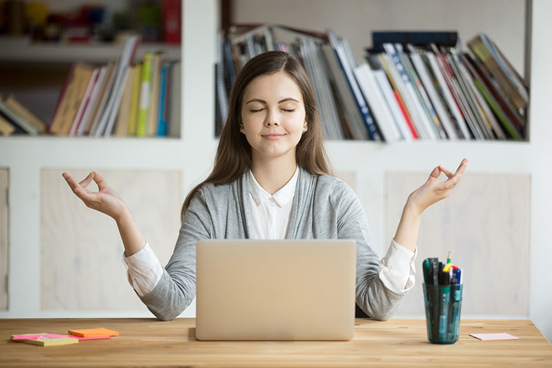 Woman meditating in front of her laptop